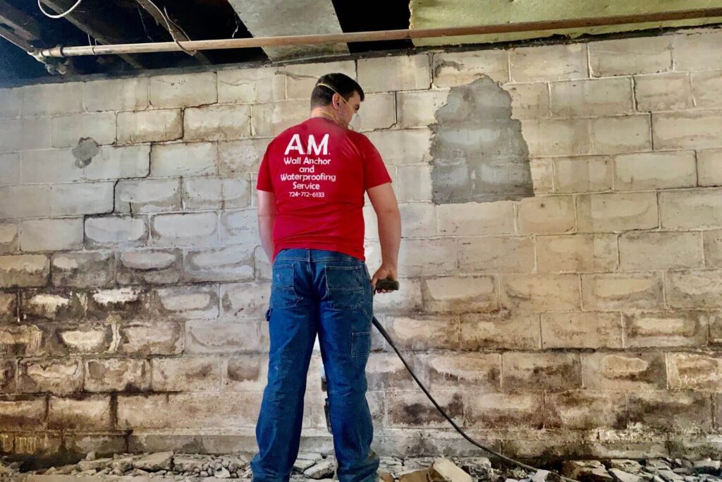 An AM Wall Anchor & Waterproofing professional is working on a sinking concrete repair project at a residential home