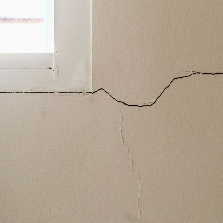 Interior of old home wall showing cracks and signs of foundation issues