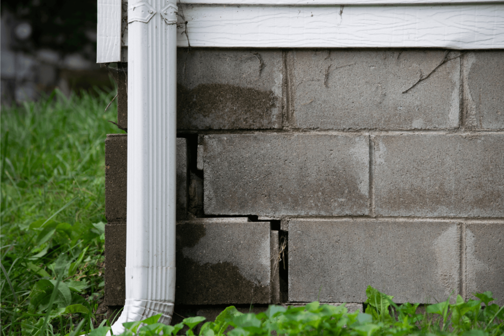 Foundation of a home with water damage, cracks, and separation in the bricks.