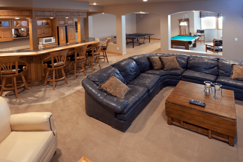 A basement with a bar, pool table, and sofa