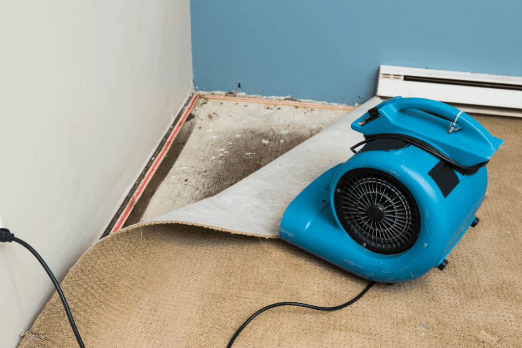 dehumidifier pointed at floor and walls that have moisture from flooding