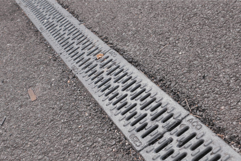 A metal trench drain, embedded in pavement, used to collect and redirect water
