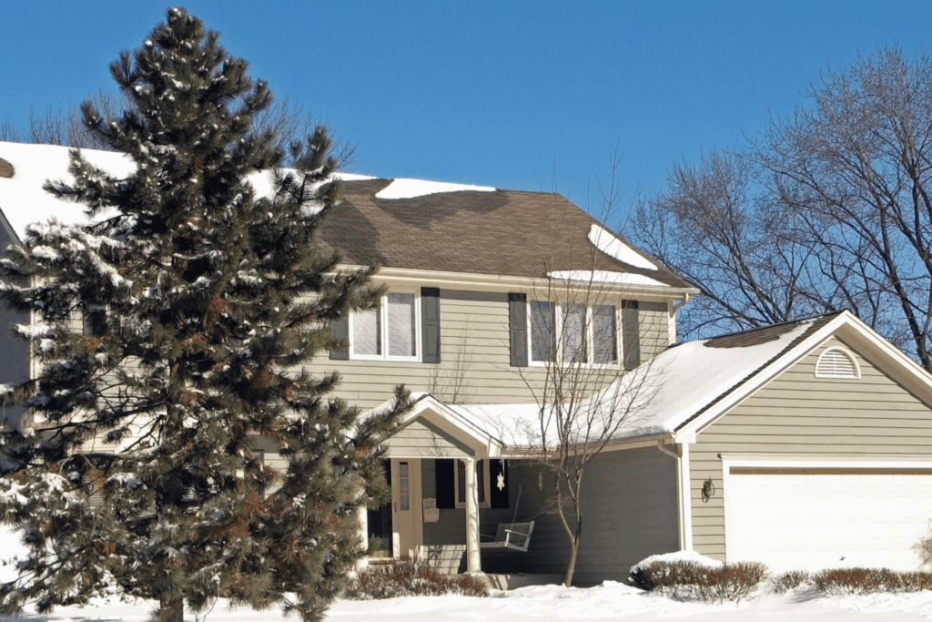 Home after snowfall showing snow melting on the roof and yard
