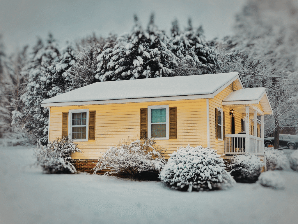 yellow house with wood shutters surrounded by snow after a winter storm