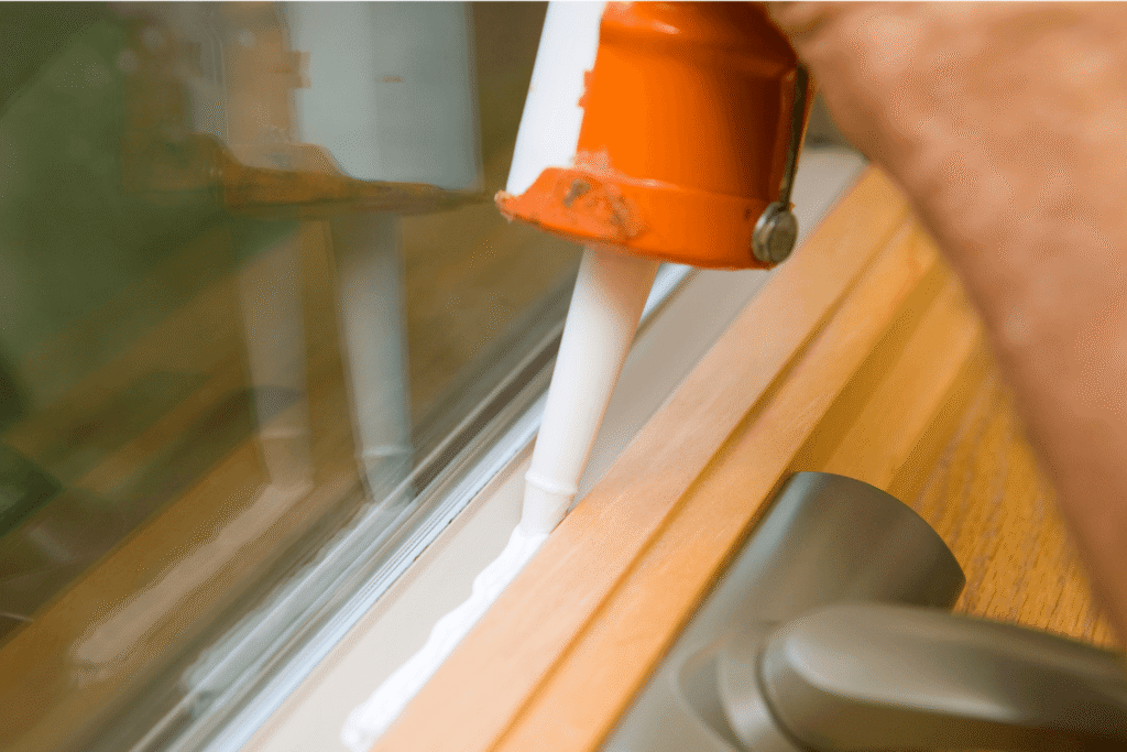 person applying caulk around a window frame